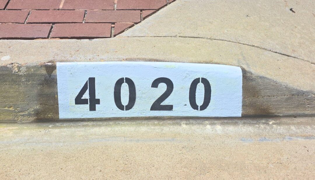 Freshly painted black curb address number on a white background in Los Angeles