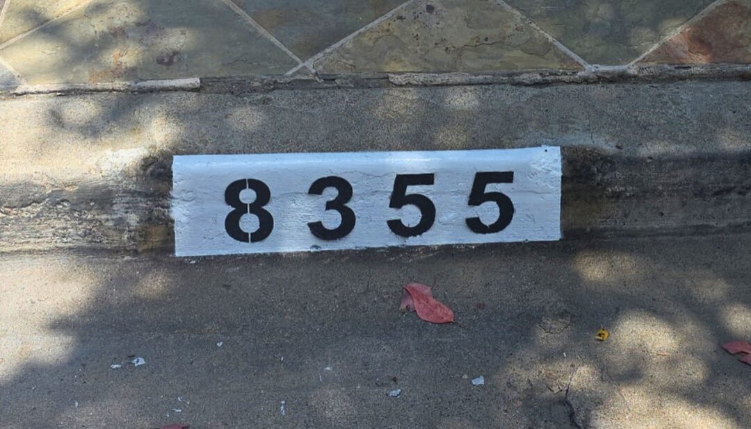 Freshly painted black curb address number on a white background in Los Angeles