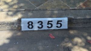 Painted curb address number 8355 in black on a white background, Los Angeles