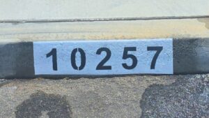 Painted curb address number 10257 in black on a white background, Los Angeles