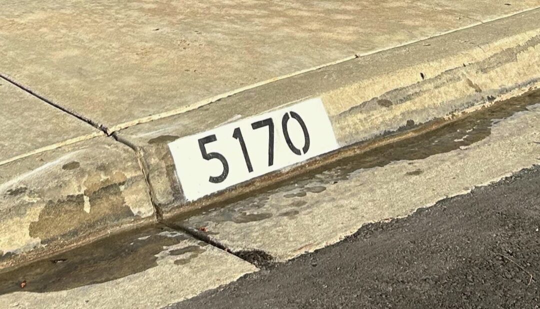 Freshly painted black curb address number on a white background in Los Angeles