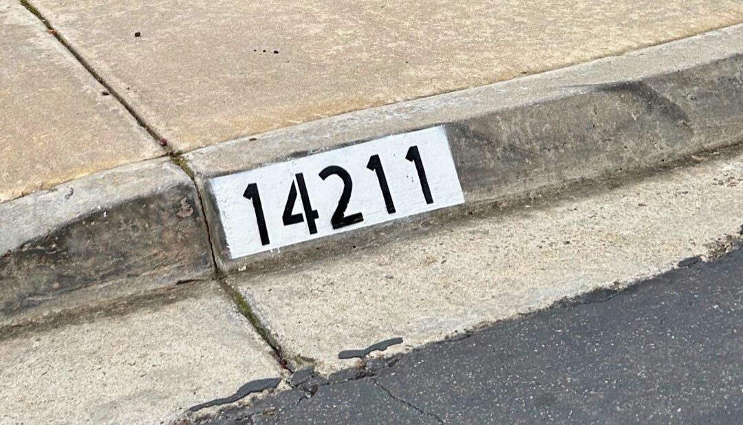 Freshly painted black curb address number on a white background in Los Angeles