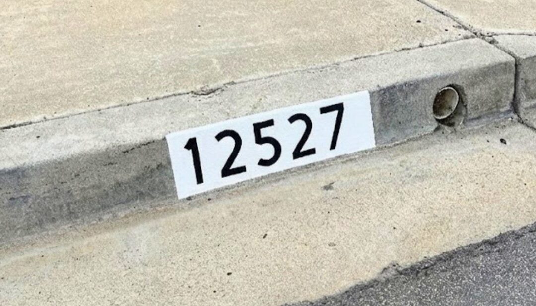 Freshly painted black curb address number on a white background in Los Angeles