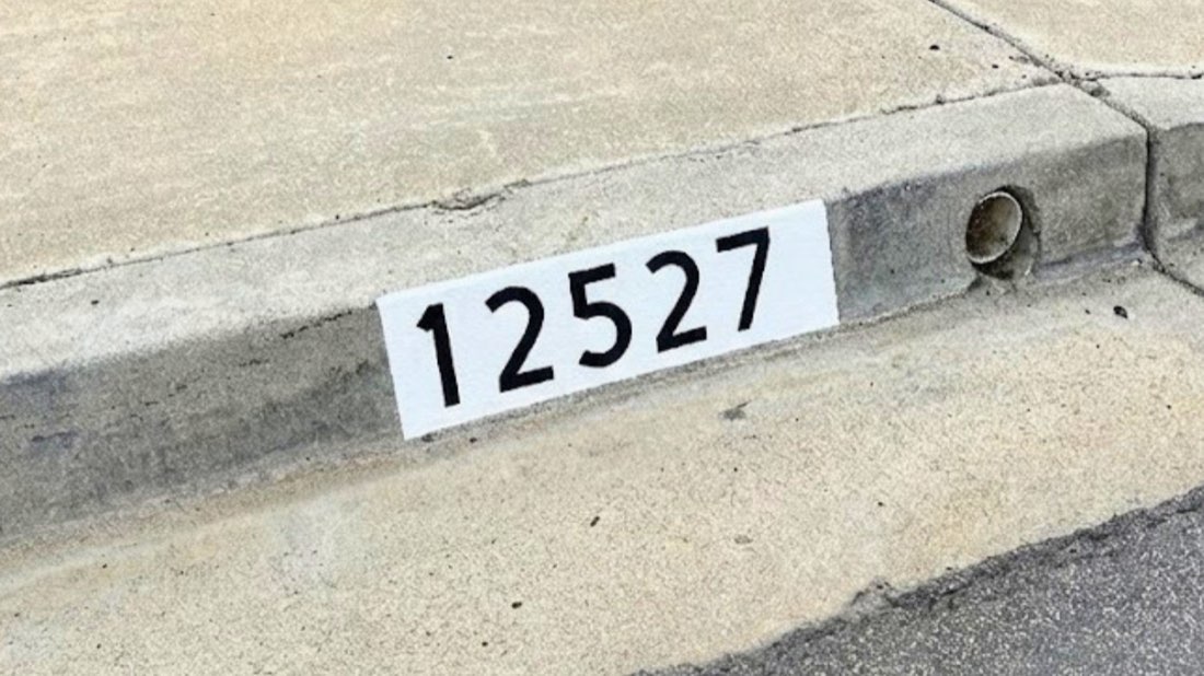 Freshly painted black curb address number on a white background in Los Angeles