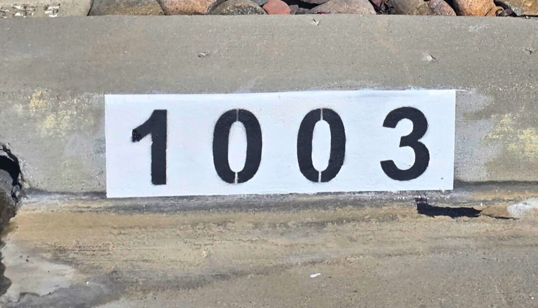 Freshly painted black curb address number on a white background in Los Angeles