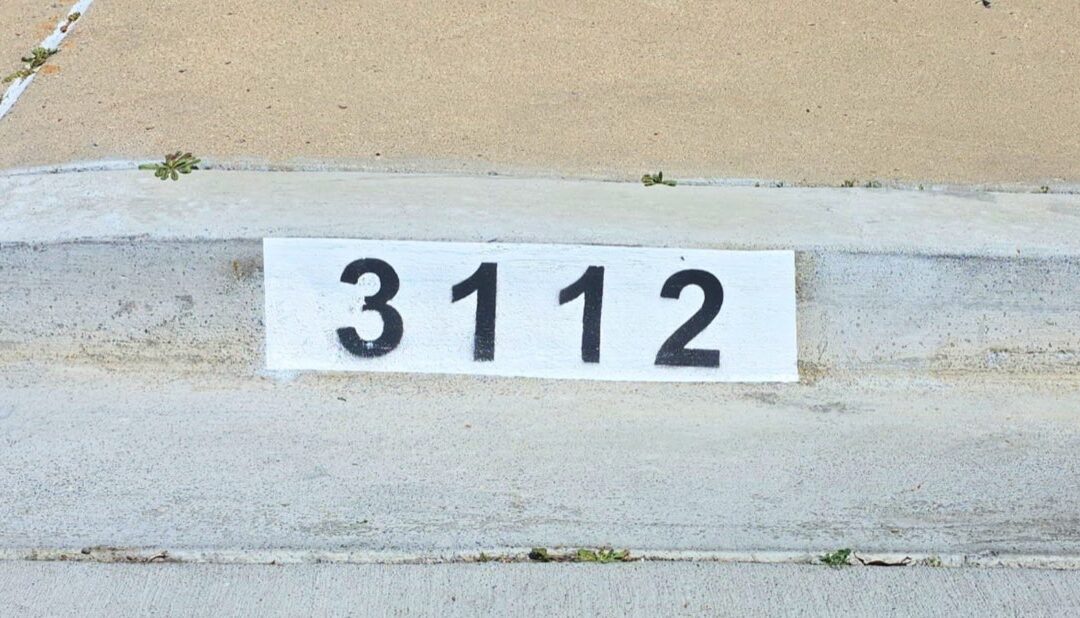 Freshly painted black curb address number on a white background in Los Angeles