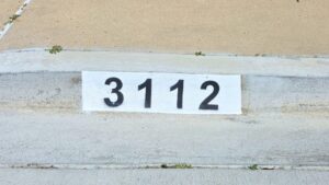 Painted curb address number 3112 in black on a white background, Los Angeles