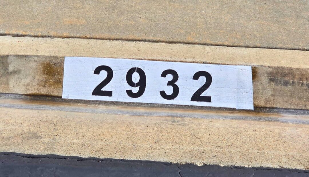 Freshly painted black curb address number on a white background in Los Angeles