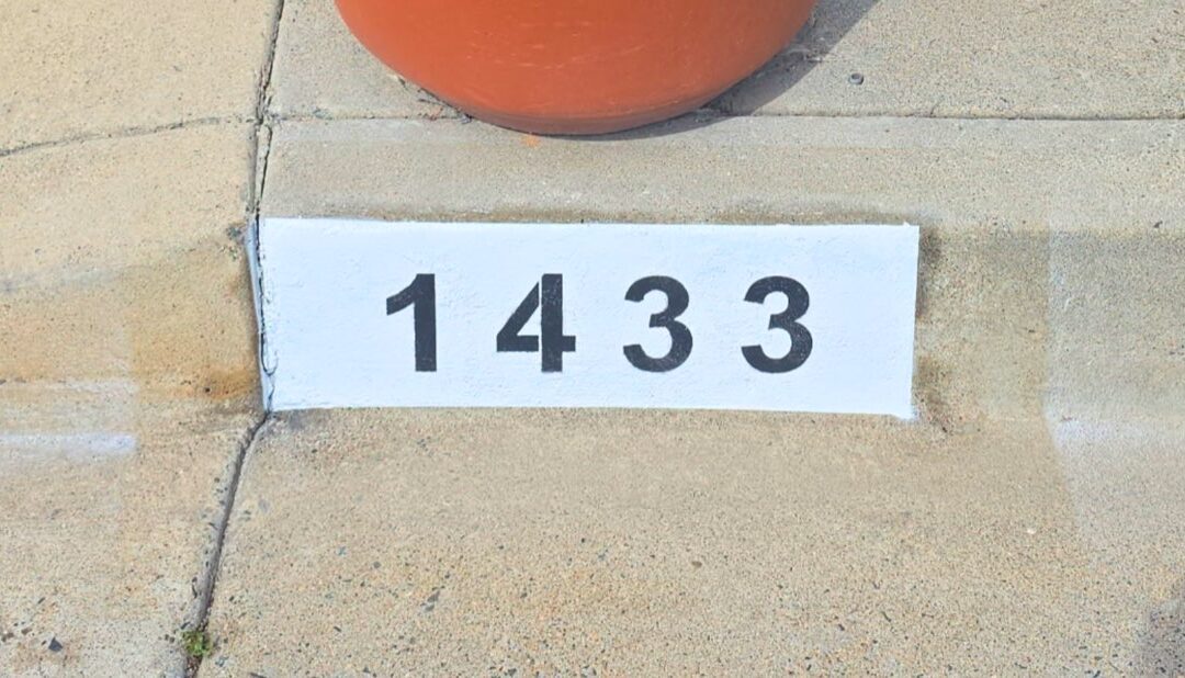 Freshly painted black curb address number on a white background in Los Angeles
